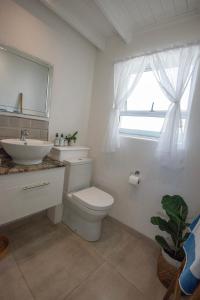 Un baño con inodoro, lavabo y ventana. en Beach Haven, en Ciudad del Cabo