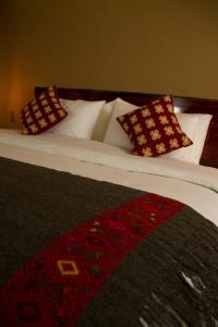 Una cama con almohadas blancas y una alfombra. en Hotel Helverica, en San Cristóbal de Las Casas