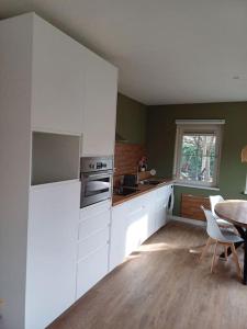cocina con armarios blancos, mesa y ventana en Natuur Appartement Dinxperlo en Dinxperlo