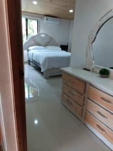 a bedroom with a bed and a mirror and a dresser at Villa Channel in Jarabacoa
