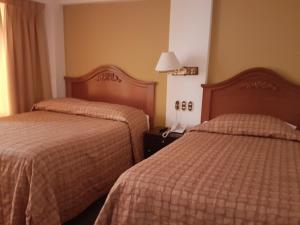 una habitación de hotel con 2 camas y una lámpara en CORONA, en Puno