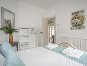 a white bedroom with two beds and a mirror at Casita in Benllech