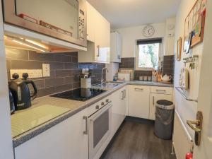 a small kitchen with white cabinets and a window at Troutbeck in Ambleside