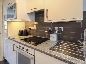 a kitchen with white cabinets and a sink at Troutbeck in Ambleside +4 photos