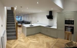 a kitchen with a staircase and a living room at Bryn Glo Cottage in Capel Curig