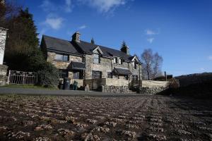 a large stone house with a field in front of it at Bryn Glo in Capel Curig