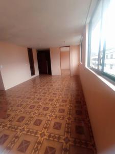 Habitación vacía con suelo de baldosa y ventana en departamento en Quito