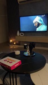 uma mesa com um livro e uma televisão num quarto em شقة بصالة مودرن وغرفة نوم em Buraydah