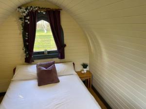 a bedroom with a bed with a window and a pillow at Belle Vista Glamping & Camping in York