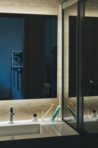 lavabo con espejo y cepillo de dientes en The Oliver Apartamentos Aravaca, en Madrid