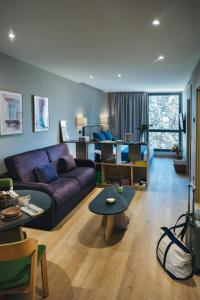 sala de estar con sofá púrpura y mesa en The Oliver Apartamentos Aravaca en Madrid