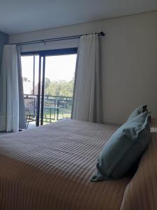 1 dormitorio con cama y ventana grande en Los Robles Apart Hotel en Sierra de la Ventana