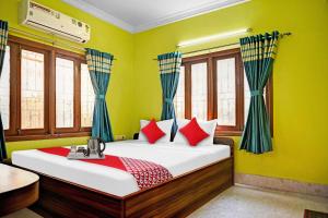 um quarto com uma cama com paredes verdes e janelas em Flagship Himgiri Guest House em Calcutá