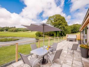 a patio with a table and chairs and an umbrella at 2 Bed in Castle Douglas 86449 in Auchencairn