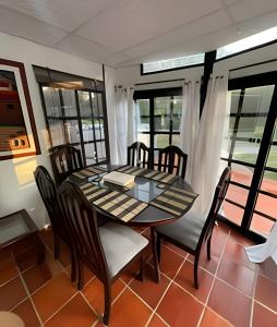 comedor con mesa, sillas y ventanas en Cabaña Campestre de con piscina, cocina, y wifi., en Carmen de Apicalá