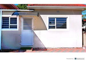 a white house with a door and two windows at One bedroom apartment. in Cape Town