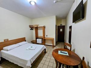a bedroom with a bed and a table and a tv at Hotel Vivenda das Cachoeiras in Brotas