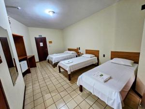 a hotel room with two beds and a bathroom at Hotel Vivenda das Cachoeiras in Brotas