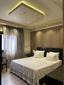 a bedroom with a large bed with white sheets at Zahran Apartment VIP شقة فندقية فاخرة in Cairo