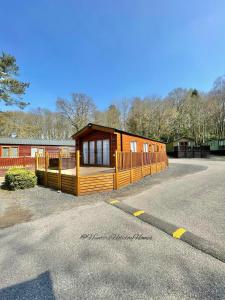 a large wooden cabin in a parking lot at Windermere View Lodge - White Cross Bay in Windermere