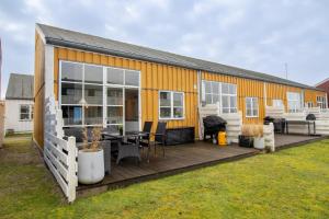 a yellow house with a deck and a table at Perle Øer Maritime ferieby Ebeltoft in Ebeltoft