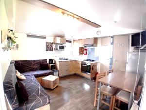 eine Küche und ein Wohnzimmer mit einem Sofa und einem Tisch in der Unterkunft Bungalow confortable à Saint-Jean-de-Monts avec terrasse in Saint-Jean-de-Monts