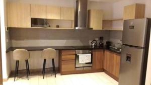 a kitchen with a stainless steel refrigerator and two chairs at &ONE Quito Parque La Carolina Alquiler por días in Quito