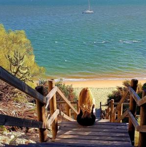 una donna seduta su un sentiero di legno per la spiaggia di APARTAMENTO DE AMY CON VISTA AL MAR 2 a Huelva