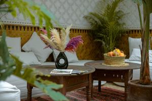 ein Wohnzimmer mit einem Sofa und Tischen mit Pflanzen in der Unterkunft Riad Darino in Marrakesch