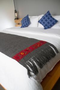 1 cama con manta blanca y negra y almohadas azules en Hotel Helverica en San Cristóbal de Las Casas