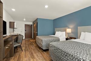 a hotel room with two beds and a desk at WoodSpring Suites Fort Collins in Fort Collins
