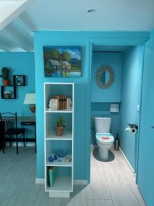 a blue bathroom with a toilet and a table at Sun Caraibes in Orient Bay