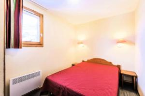 1 dormitorio con cama roja y ventana en Résidence Les Valmonts - maeva Home - Appartement 4 Pièces 8 Personnes - Séle 41, en Saint-Martin-de-Belleville