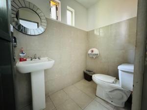 a bathroom with a sink and a toilet and a mirror at La Luz Hostal Cancun in Cancún