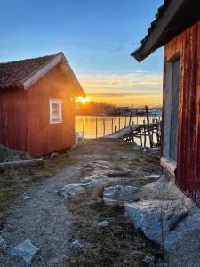 a building next to a dock with the sunset in the background at Bestemors hus - med kystnær beliggenhet in Fredrikstad