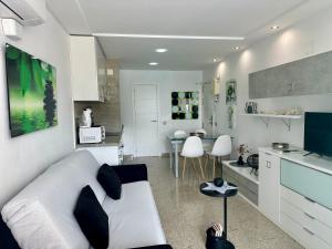 een woonkamer met een witte bank en een keuken bij Estudios HORIZONTE BEACH in Calpe