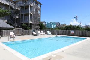 a swimming pool with chairs and a fence at Carried Away #16-IC in Avon