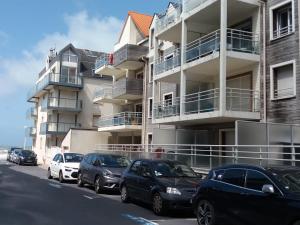 a row of cars parked in front of a building at Superbe apt cosy, 50m de la plage, 4 pers, vue côté mer in Fort-Mahon-Plage