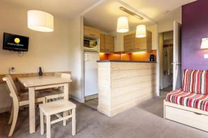 Mâcot La PlagneにあるRésidence Plagne Lauze - maeva Home - Appartement 2 Pièces 5 Personnes - Sélection MAE-3504のテーブルと椅子のあるキッチンとダイニングルーム