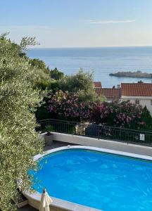 a blue swimming pool with a view of the ocean at Apartments Kentera LUX in Sveti Stefan