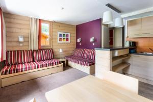 uma sala de estar com dois sofás vermelhos e uma cozinha em Résidence Plagne Lauze - maeva Home - Appartement 2 Pièces 5 Personnes - Séle 74 em Mâcot La Plagne
