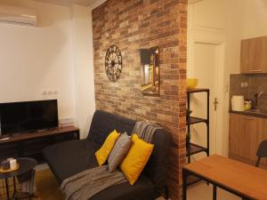 a living room with a couch and a brick wall at Cozy Studio next to Acropolis & Plaka in Athens