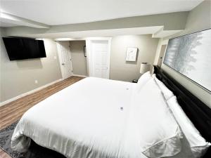 een slaapkamer met een wit bed en een flatscreen-tv bij Boardwalk- large modern unit with King bed fast WIFI free coffee and easy parking in Wilmington