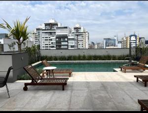 un patio avec deux bancs et une piscine avec des bâtiments dans l'établissement Studio charmoso, próximo à Av. Paulista, à São Paulo