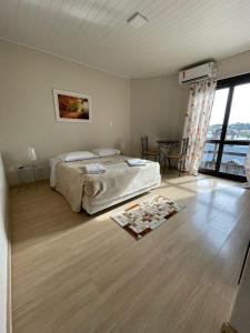 1 dormitorio con cama y ventana grande en Pousada Folhas de Outono, en Canela
