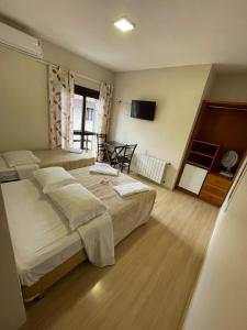 Habitación de hotel con 2 camas y TV en Pousada Folhas de Outono en Canela