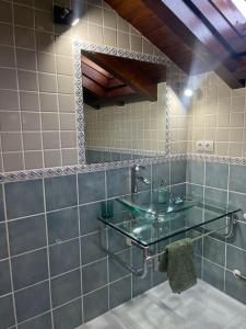uma casa de banho com um lavatório de vidro e um espelho. em Villa San Miguel em Cudón