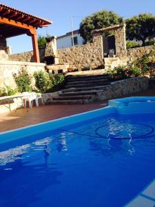 a blue swimming pool with a house in the background at Valdebruna ll y de Gredos in Navaluenga