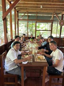 a group of people sitting around a wooden table at Passiflora Camp in Puerto Maldonado