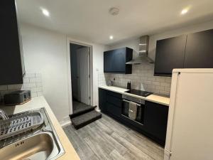 a kitchen with a sink and a refrigerator at Brand new refurb 8 person house in Hull